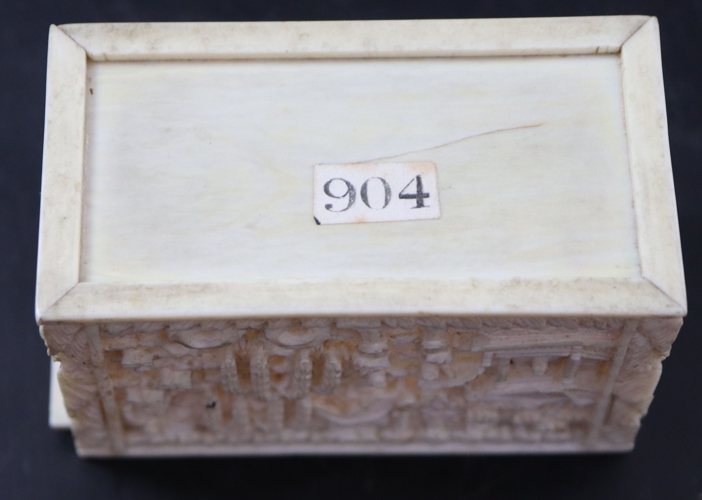 A 19th century Chinese relief carved ivory box housing plain and red stained ivory alphabet letters, 6.75cm